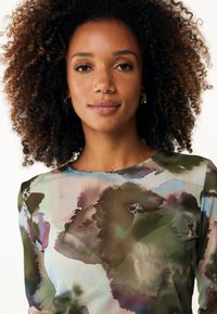 Bedruckte Bluse mit einem fließenden Design in Grüntönen, Lila und Blau. Lange Ärmel, runder Ausschnitt und ein weicher, strukturierter Stoff.