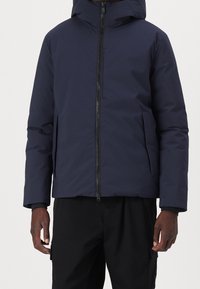 Mørkeblå vinterjakke med hætte, der har en frontlynlås og sidelommer. Glat tekstur og tætsiddende design med en skræddersyet silhuet.