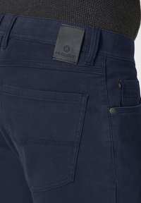 Navy blue pants with a smooth texture, featuring a leather tag labeled "redpoint," and multiple pockets with subtle stitching details.