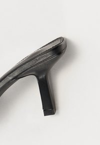 Sandale noire à talons hauts avec un design élégant, tige en cuir lisse, semelle texturée et forme de talon carré.