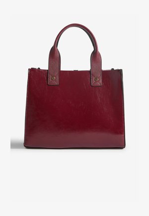Burgundi nahast kott tekstureeritud käepidemete ja metallaktsentidega. Ristkülikukujuline kuju, sile pind, kahe ülemise käepidemega mugavaks kandmiseks.
