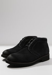 Stivaletti neri in suede con punta arrotondata, lacci, cuciture a contrasto e suola in gomma testurizzata.
