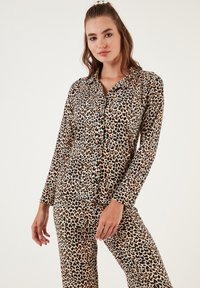 Set pidžame s leopardskim uzorkom, dugim rukavima, gumbima sprijeda i odgovarajućim hlačama. Meki materijal, opušten kroj i kontrastni akcenti.