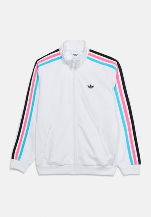Veste de survêtement blanche à fermeture éclair avec des rayures noires, roses et bleues sur les manches et un petit logo Adidas noir sur la poitrine.