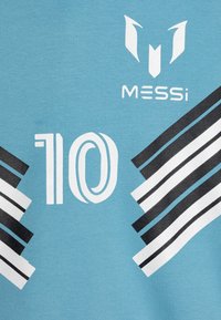 Világoskék sportmez, amelyen fehér "10" és "MESSI" felirat található, fekete-fehér diagonális csíkokkal díszítve az alsó oldalakon.