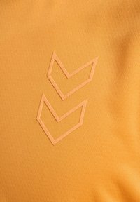 Orange textil med en strukturerad yta som har två lager av kontrasterande chevronmönster i en ljusare nyans, sydda på tyget.