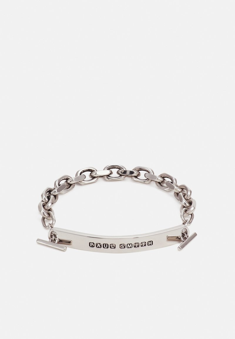 Bracelet chaîne en argent avec une plaque rectangulaire gravée du nom « Paul Smith » en lettres majuscules noires.