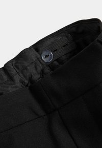 Fascia in tessuto nero con chiusura a bottone e passanti per la cintura, caratterizzata da una texture liscia e cuciture piatte. Attenzione ai dettagli delle cuciture.