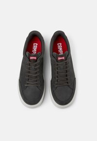 Graue Wildledersneaker mit Gummisohlen, Schnürdesign und auffälligem roten Innenfutter mit "CAMPPER"-Logo auf der Zunge.