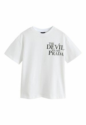 Hvid T-shirt med korte ærmer og sort tekst på venstre bryst, der siger "The Devil Wears Prada" i forskellige skriftstørrelser.