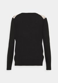 Pull en maille noire avec manches longues, encolure ronde et accents beiges contrastants sur les épaules. Texture lisse et coupe ajustée.