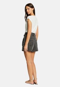 Pantalones cortos de denim gris con cintura alta, cuatro bolsillos y un ajuste relajado, combinados con una camiseta blanca ajustada y sandalias planas.