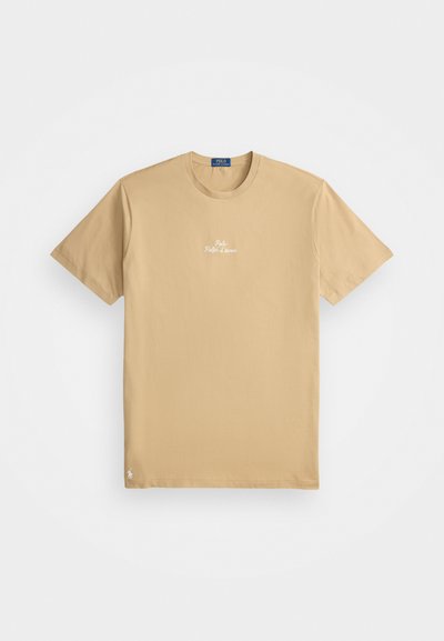 Bežinis marškinėliai trumpomis rankovėmis su apvaliu kaklu, "Polo Ralph Lauren" logotipas baltos spalvos, centruotas krūtinėje, mažas siuvinėtas emblema arčiau apačios.