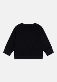 Sudadera negra con mangas largas, escote redondo y tela texturizada. La parte posterior muestra un detalle de costura minimalista y un acabado suave.