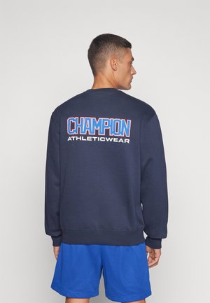 Sudadera azul marino con cuello redondo, logo en blanco y rojo "CHAMPION ATHLETICWEAR" en la parte posterior, puños y dobladillo acanalados.