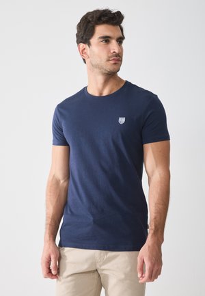 Navy blue cotton t-shirt with short sleeves, round neck, and small logo detail on the chest. Smooth texture, fitted design.