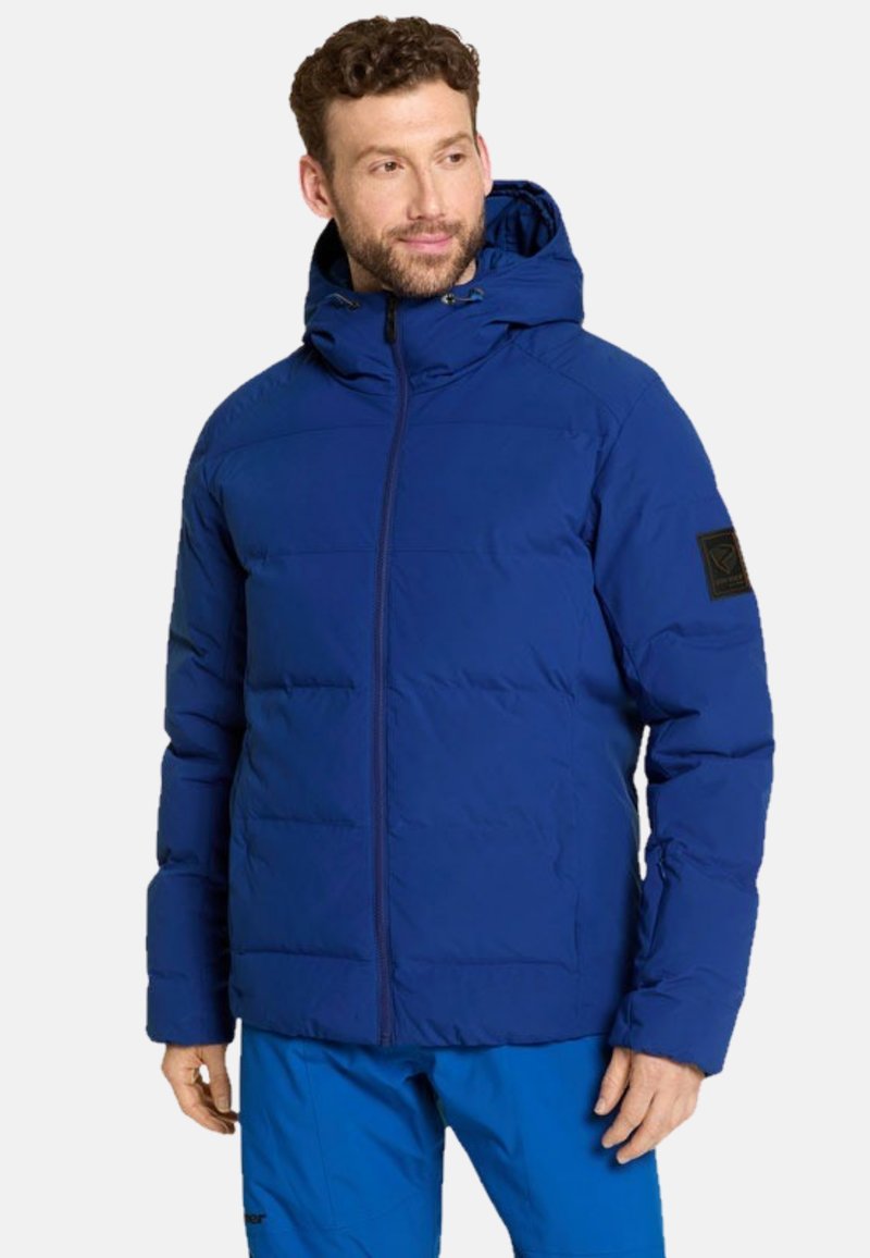 Blå puffjacka med huva, med dragkedjestängning och horisontell sömnad. Inkluderar en svart logopatch på vänster ärm.