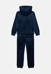 Tumesinise veluurtagsega dressipluus kapuutsiga ja sobivate pükstega. Sile tekstiil, soonikkoes varrukad ja mugav lõige.