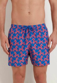Shorts de bain avec un fond bleu et un motif d'animaux en ballon roses, taille avec cordon de serrage et tissu léger.