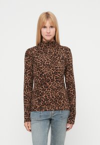 Τοπ με ζιβάγκο σε λεοπάρ μοτίβο σε καφέ και μαύρο, μακριά μανίκια, ελαστικό ύφασμα, εφαρμοστό σχέδιο, συνδυασμένο με ανοιχτό μπλε τζιν.