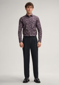 Mehrfarbiges Blumenhemd mit Button-Down-Kragen, langen Ärmeln und dunkler, taillierter Hose. Glatte Textur und taillierter Schnitt.