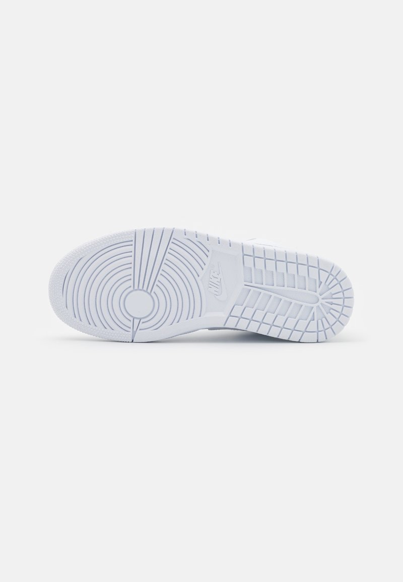 Baskets de sport blanches avec une semelle en caoutchouc texturé présentant des motifs de cercles concentriques et des accents en grille. Logo embossé sur le côté.