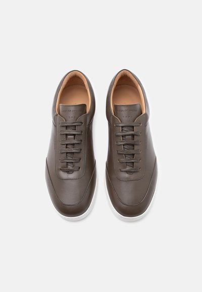 Ζευγάρι καφέ δερμάτινων αθλητικών παπουτσιών με κορδόνια, λευκές σόλες, μπεζ εσωτερική επένδυση και το λογότυπο «Tiger of Sweden» ανάγλυφο στη γλώσσα.