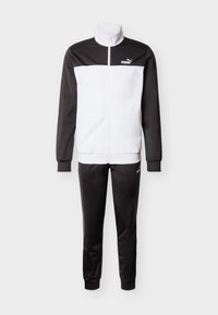 Černo-bílá souprava Puma se zipovou bundou a odpovídajícími kalhotami, s logem na hrudi a stehen.