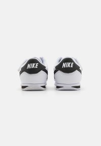 Bijele i crne Nike tenisice, s glatkim sintetičkim gornjim dijelom, podstavljenim ovratnikom i istaknutim logotipima na peti.