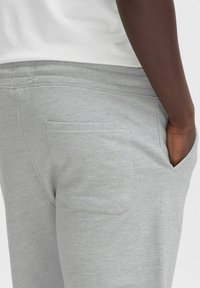 Pantalons de survêtement gris en mélange de coton doux, dotés d'une pochette arrière et d'une taille réglable pour un confort optimal.