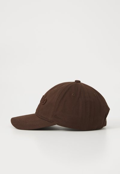 Brown baseball cap with curved brim, visible stitched eyelets, and embroidered text on a white background, shown from left side.