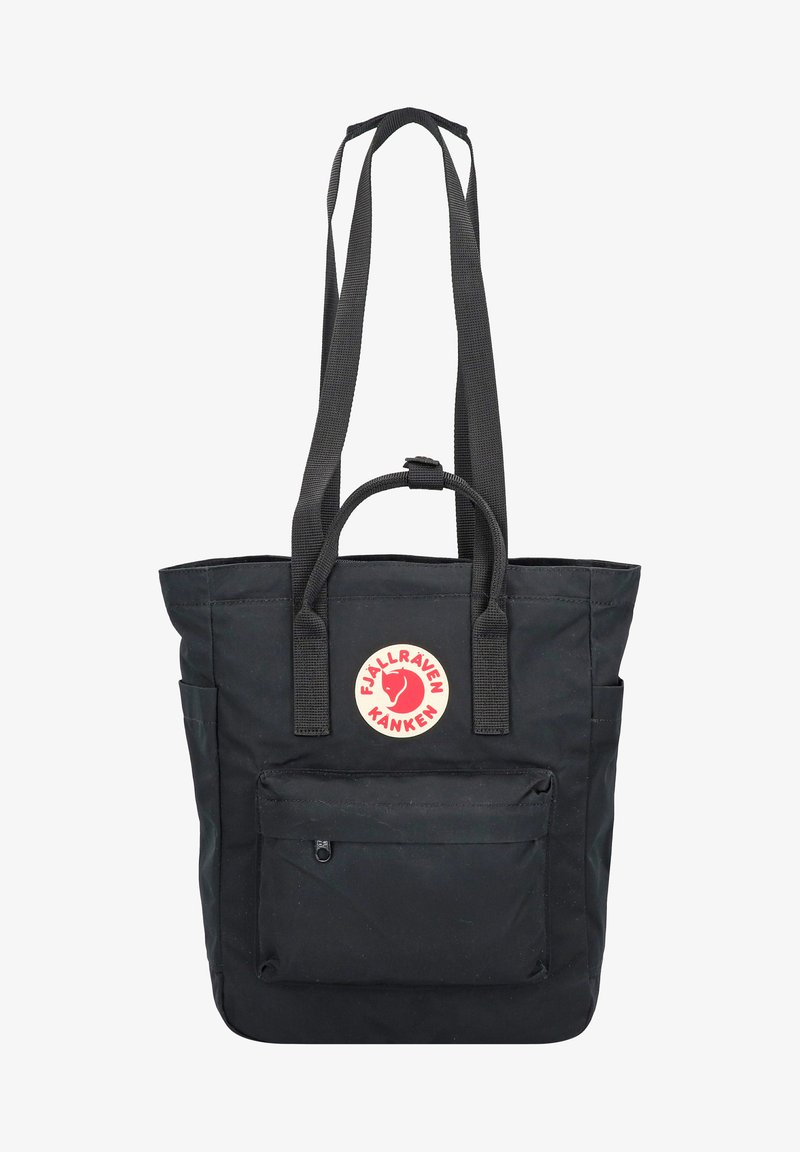 Musta kassi, joka on valmistettu kestävästä kankaasta. Tässä kassissa on yläkahva, pitkät olkahihnat sekä etupuolella vetoketjullinen tasku, jossa on punainen pyöreä logo.