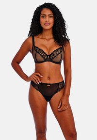 Zwart lingerie set van kant met een bralette met bloemmotief en doorzichtige panelen, vergezeld van bijpassende doorzichtige slipjes.
