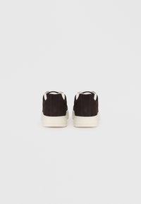 Black suede sneakers with white rubber soles and lace-up closure, featuring contrasting white accents on the tongue and heel.