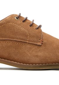 Brown suede shoe with a rounded toe, contrasting stitching, and three brown laces through metal eyelets. Flat rubber sole.