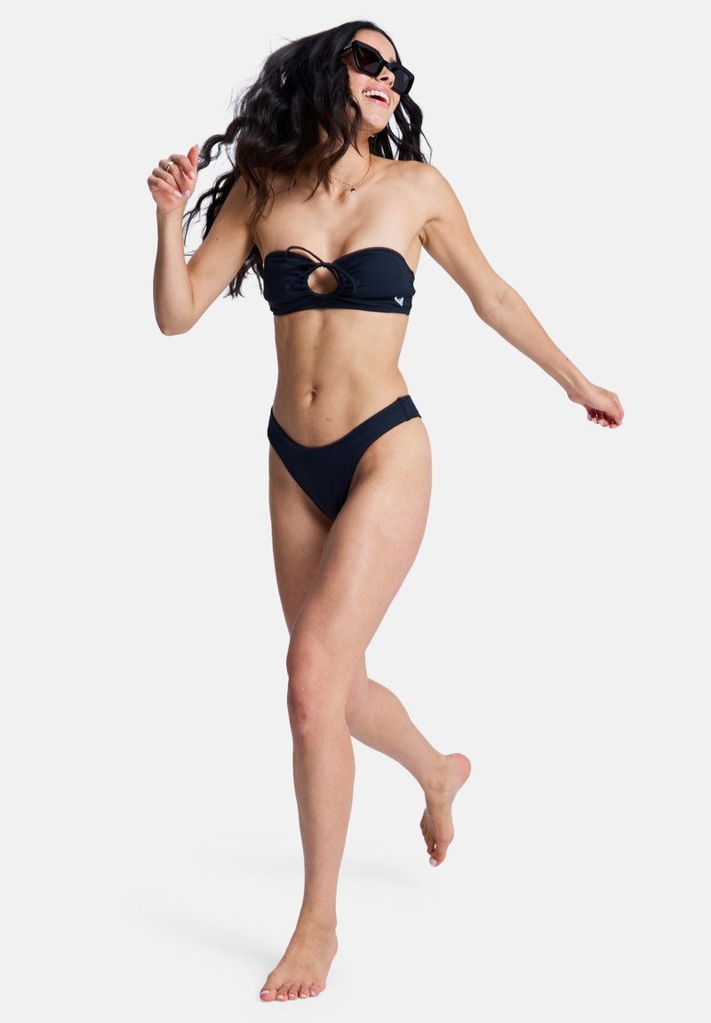 Ensemble bikini noir composé d'un haut bandeau sans bretelles avec une découpe à l'avant et d'un bas taille haute, fabriqué en matière lisse et extensible.