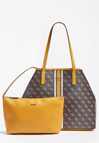 Duża brązowa torba na ramię z żółtymi akcentami i logo, charakteryzująca się paskowanym wzorem; obok niej znajduje się mała, pasująca żółta kosmetyczka na zamek.