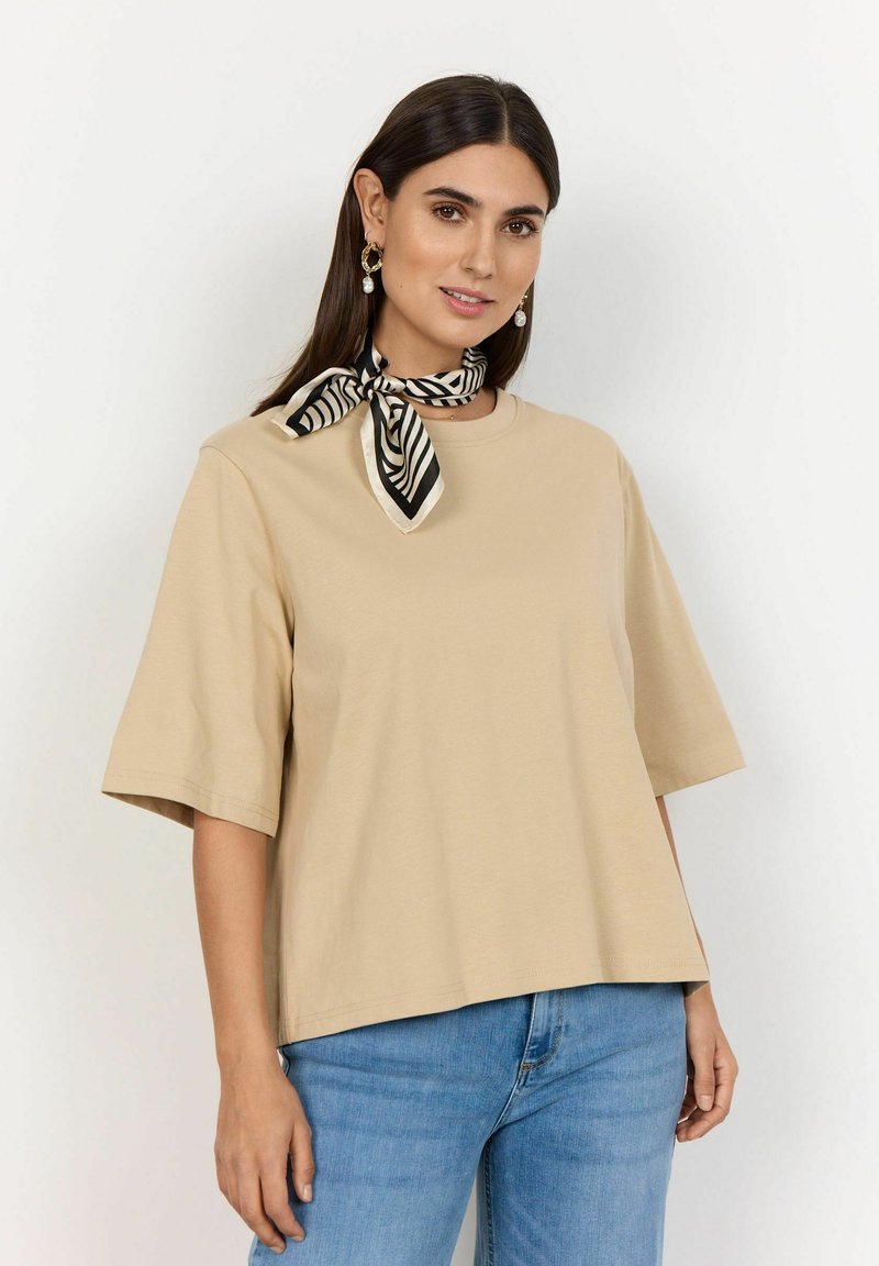Beige kortærmet T-shirt med rund hals, afslappet pasform, parret med et sort-hvidstribet tørklæde om halsen.