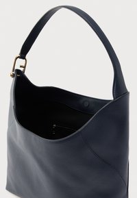 Tamnoplava kožna torba glatke teksture, zakrivljenog oblika i jednim remenom za nošenje preko ramena. Sadrži unutarnji džep s patentnim zatvaračem za organizaciju.
