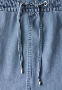 Lyseblå denimshorts med en samlet elastisk talje, sølvspidse snore og lodrette syninger. Afslappet design.