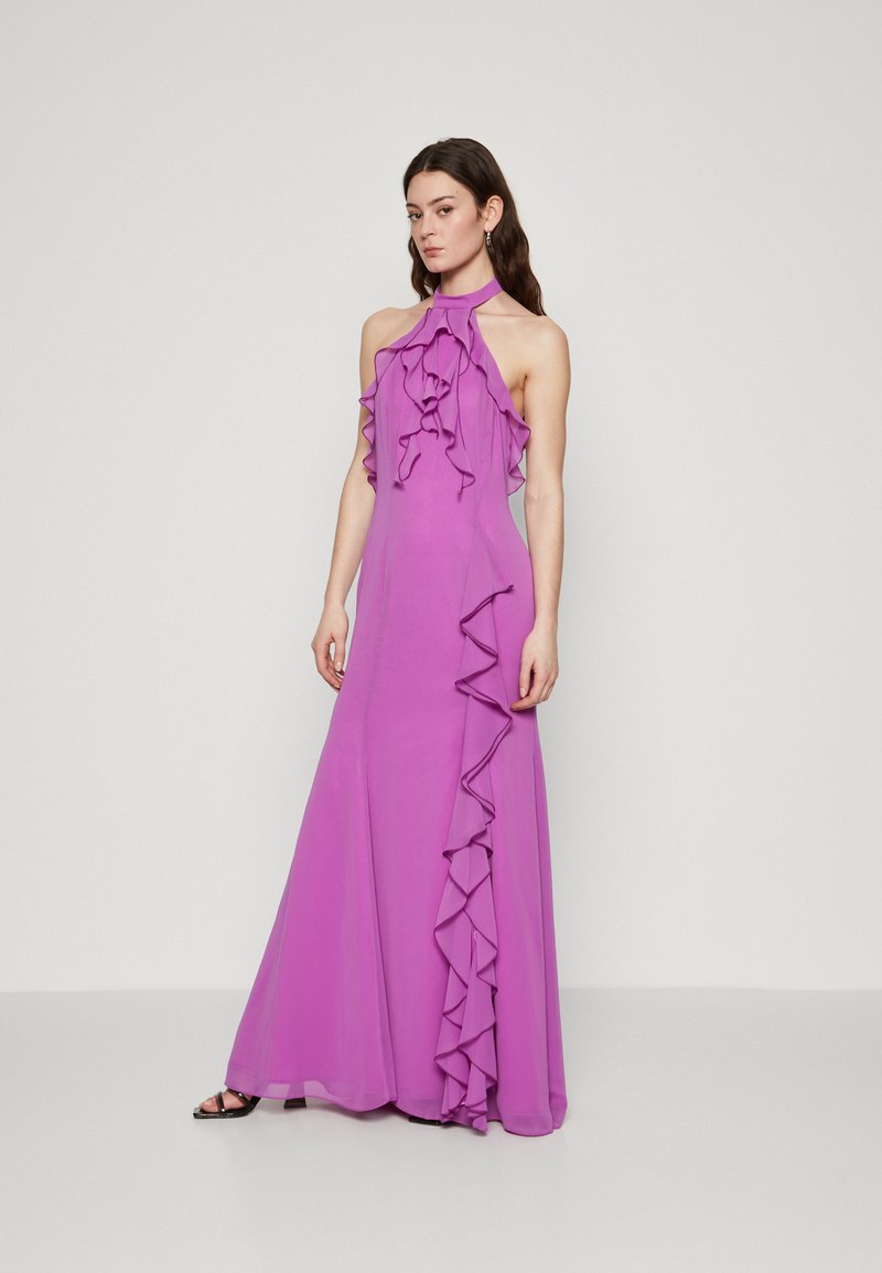 Robe de soirée à encolure halter en tissu violet éclatant. Présente des accents volants sur le devant et une silhouette ajustée qui tombe jusqu'au sol.