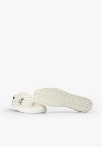 Sneakers in off-white leather with a textured rubber sole. Features black accents and a stitched logo on the side. Rounded toe design.