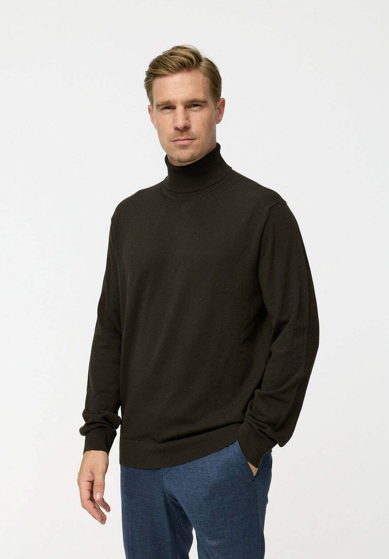 Sötétbarna garbós pulóver, puha anyagból, hosszú ujjal és bordázott aljjal, kék nadrággal párosítva. Egyszerű, hétköznapi dizájn.