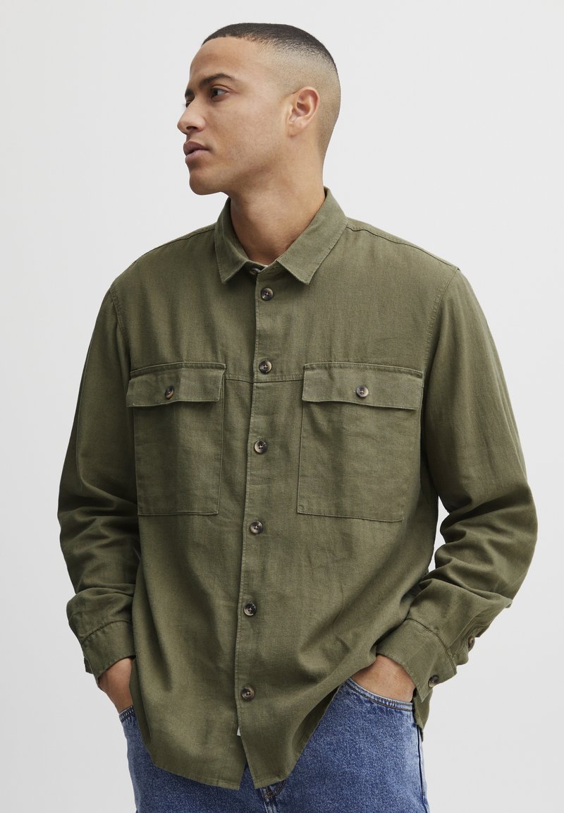 Olijfgroene button-up shirt van een gestructureerde stof met twee voorzakken, voorzien van bruine knopen en een klassieke kraagstijl.