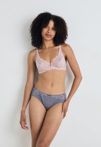 Lace bralette in zacht roze met golvende randen, gecombineerd met grijze slips met bloemenkantaccenten op de tailleband. Zachte textuur.