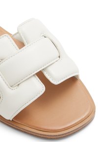 Sandale glissante en cuir blanc avec de larges lanières au toucher lisse, des coutures contrastantes et une semelle intérieure rembourrée beige.
