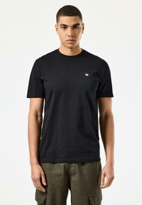 Zwart T-shirt met korte mouwen van katoen, met een ronde hals en een klein vierkant logo op de borst, gedragen met olijfgroene cargobroek.