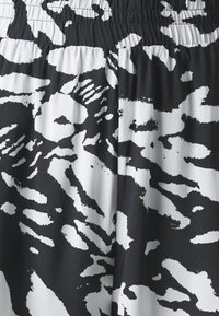 Tissu imprimé animal abstrait en noir et blanc avec une ceinture élastique froncée.