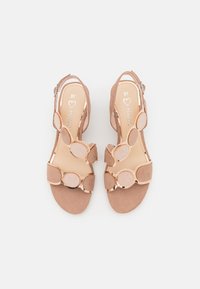 Sandales à talons en suède marron avec de grands accents circulaires, un bout fermé et une fermeture éclair à l'arrière. Taille 37. Doublure intérieure lisse.