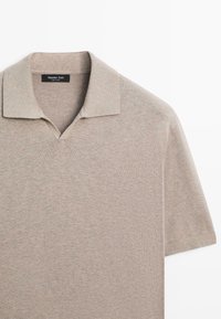 Polo en maille beige à manches courtes avec col et décolleté en V, étiquette Massimo Dutti.